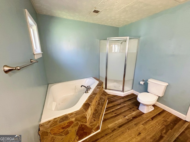 bathroom featuring hardwood / wood-style flooring, independent shower and bath, toilet, and a textured ceiling