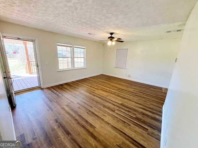 spare room featuring ceiling fan, dark wood-type flooring, and a textured ceiling