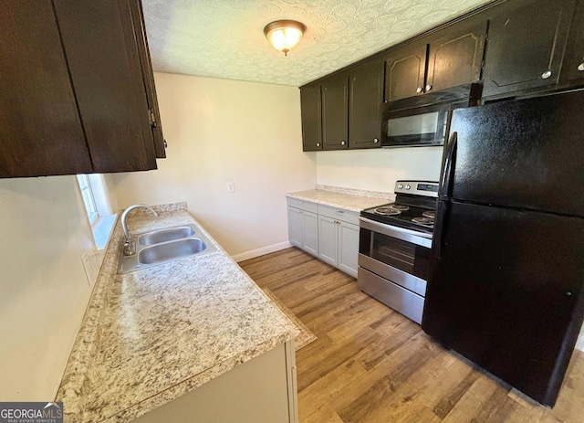 kitchen featuring light wood-type flooring, dark brown cabinetry, a textured ceiling, black appliances, and sink