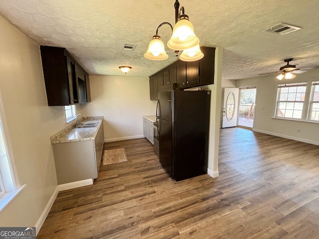 kitchen with black refrigerator, dark brown cabinetry, sink, a textured ceiling, and hardwood / wood-style floors