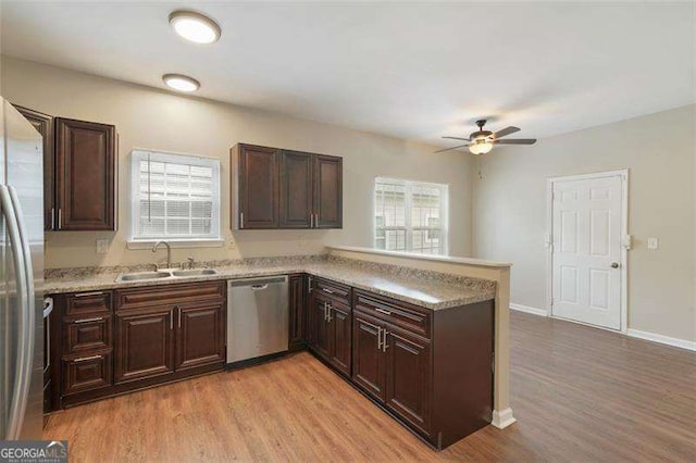 kitchen with appliances with stainless steel finishes, sink, light hardwood / wood-style floors, ceiling fan, and kitchen peninsula