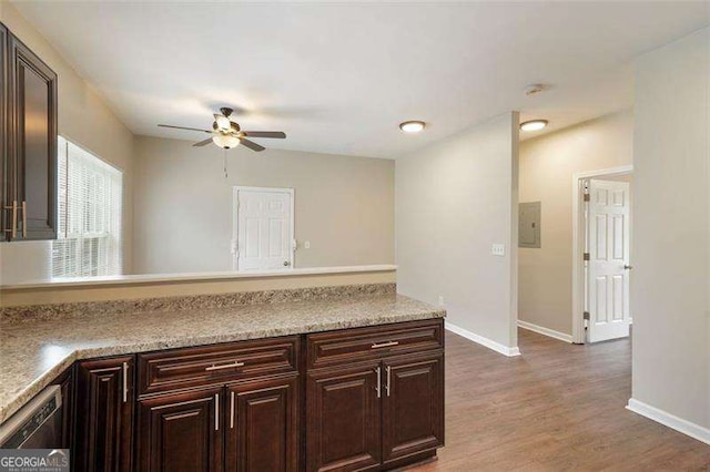 kitchen with light stone counters, dark brown cabinets, dark hardwood / wood-style floors, and ceiling fan