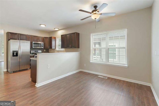 kitchen with light hardwood / wood-style floors, plenty of natural light, stainless steel appliances, and kitchen peninsula