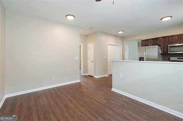 kitchen featuring appliances with stainless steel finishes, dark brown cabinetry, dark hardwood / wood-style floors, and decorative backsplash