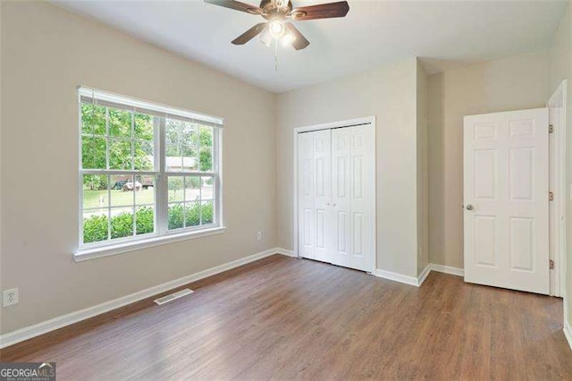 unfurnished bedroom featuring ceiling fan, dark hardwood / wood-style floors, and a closet