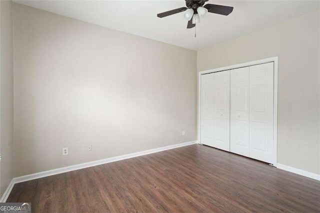 unfurnished bedroom with dark wood-type flooring, ceiling fan, and a closet