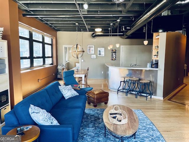 living area featuring a notable chandelier, wood finished floors, and baseboards