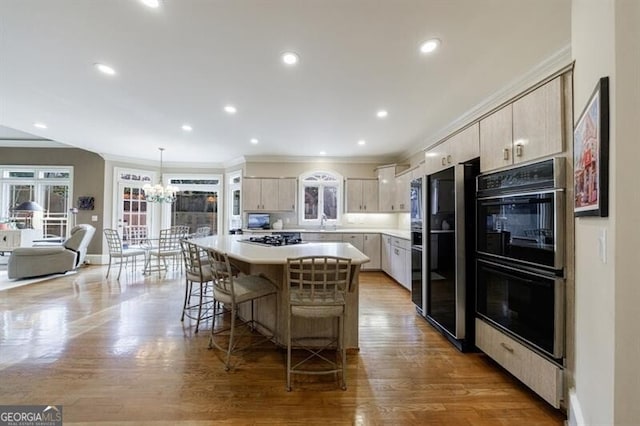 kitchen with double oven, wood-type flooring, a kitchen island, decorative light fixtures, and stainless steel gas cooktop