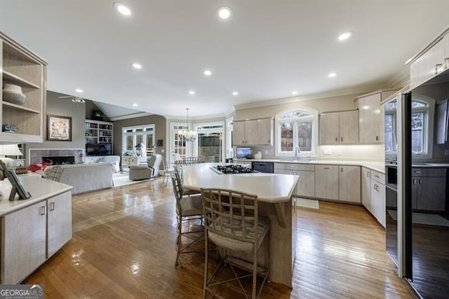 kitchen with hanging light fixtures, a center island, light hardwood / wood-style floors, sink, and vaulted ceiling