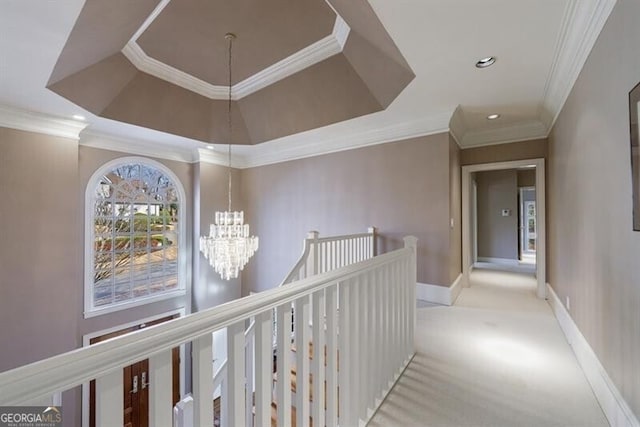 hall featuring a tray ceiling, crown molding, light colored carpet, and an inviting chandelier