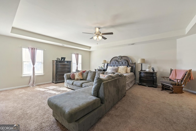 bedroom with ceiling fan, a raised ceiling, and light colored carpet