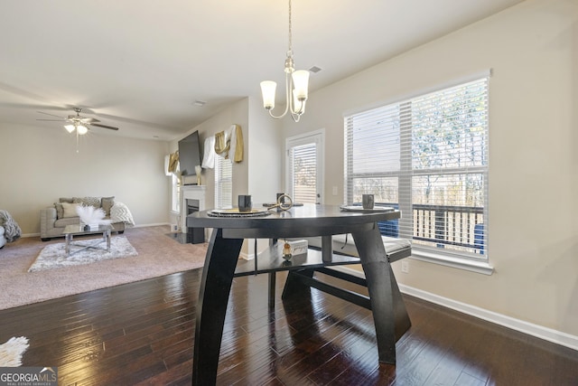 dining room with ceiling fan with notable chandelier and dark hardwood / wood-style floors