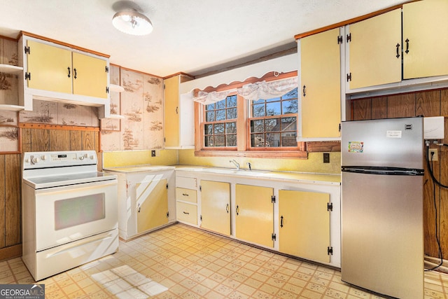 kitchen with light floors, white range with electric cooktop, light countertops, freestanding refrigerator, and a sink