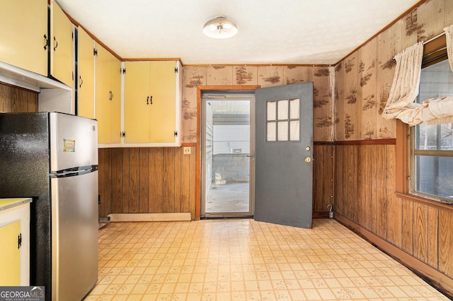 kitchen featuring light floors, freestanding refrigerator, and wooden walls