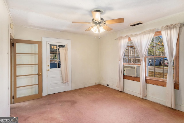 empty room featuring carpet, visible vents, a ceiling fan, ornamental molding, and cooling unit