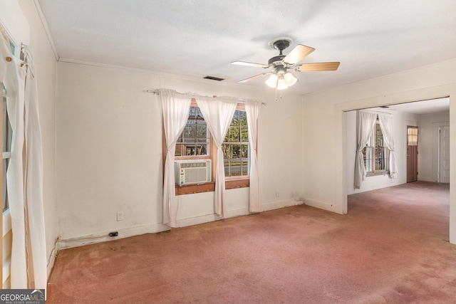 carpeted spare room featuring cooling unit, visible vents, baseboards, a ceiling fan, and crown molding