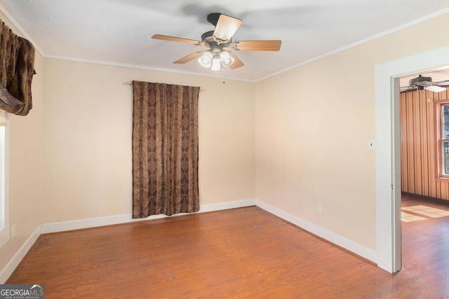 unfurnished room featuring baseboards, wood finished floors, a ceiling fan, and crown molding