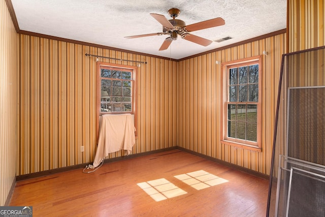 spare room featuring a textured ceiling, ornamental molding, and wood finished floors