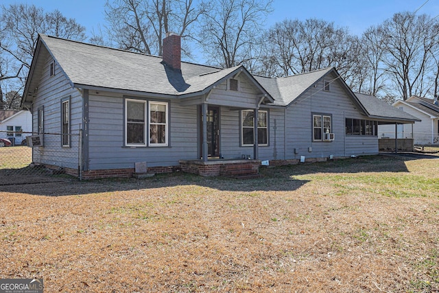 view of front of home featuring a chimney, roof with shingles, fence, cooling unit, and a front lawn