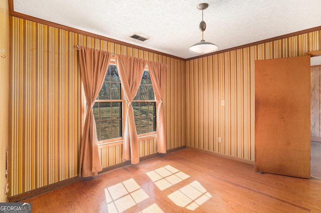 unfurnished room with visible vents, a textured ceiling, and wood finished floors