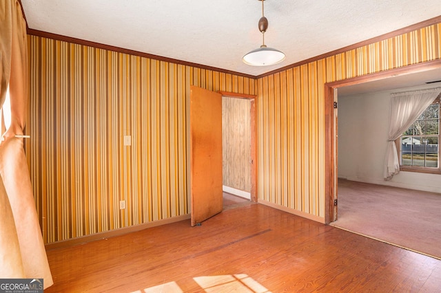 unfurnished room featuring crown molding, baseboards, and wood finished floors