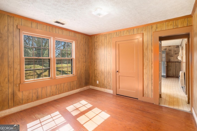 unfurnished room featuring visible vents, crown molding, a textured ceiling, and wood finished floors