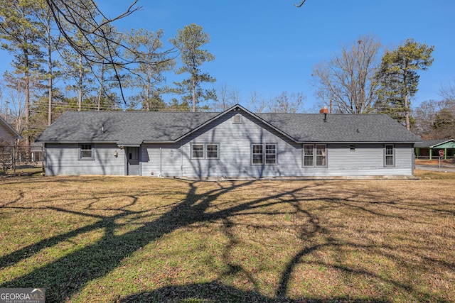 back of property featuring a shingled roof, fence, and a lawn