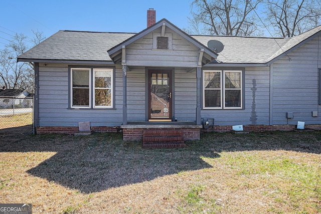 bungalow-style house featuring a shingled roof, fence, a chimney, and a front lawn