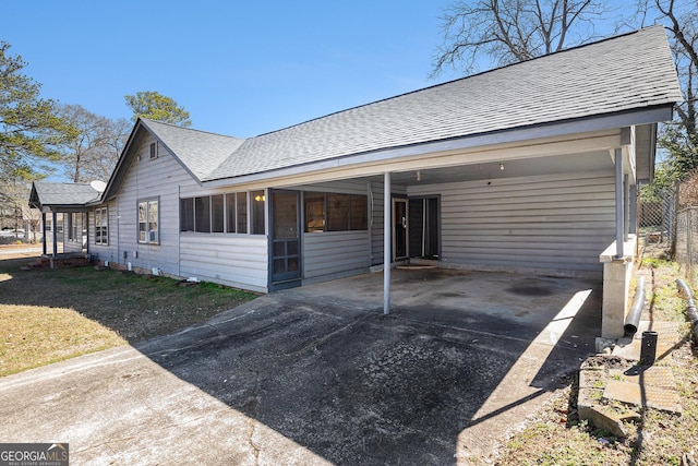 ranch-style home featuring driveway, an attached carport, and roof with shingles