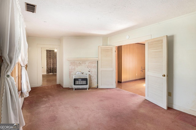 unfurnished living room with visible vents, light colored carpet, ornamental molding, heating unit, and a textured ceiling