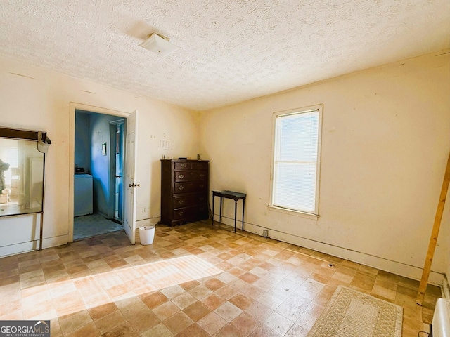 unfurnished bedroom with a textured ceiling and washer / dryer