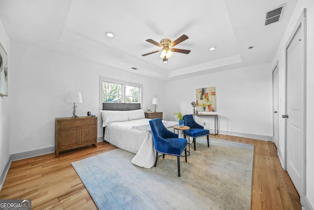 bedroom with a tray ceiling, ceiling fan, and wood-type flooring