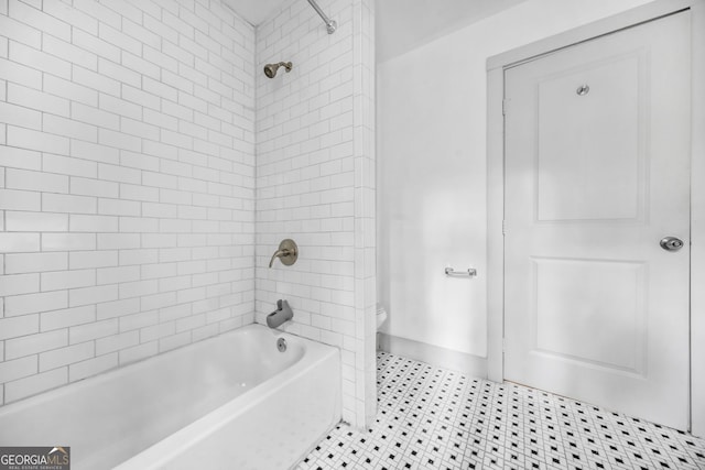 bathroom with toilet and tiled shower / bath