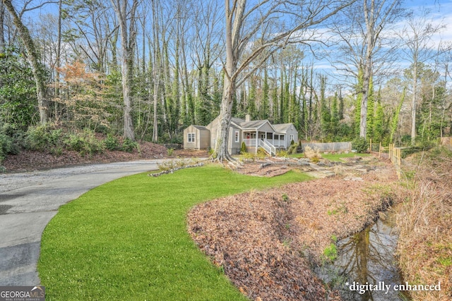 view of front of house featuring a porch, a storage shed, and a front yard