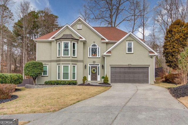 traditional-style home featuring stucco siding, an attached garage, concrete driveway, and a front lawn