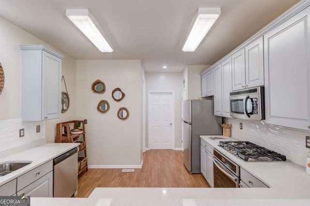 kitchen featuring light countertops, light wood-style floors, tasteful backsplash, and stainless steel appliances