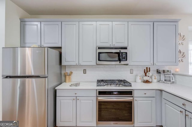 kitchen with tasteful backsplash, appliances with stainless steel finishes, and light countertops