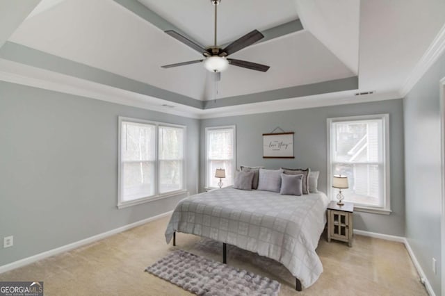 bedroom featuring crown molding, baseboards, light colored carpet, a raised ceiling, and a ceiling fan