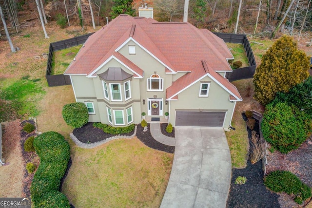 view of front facade with stucco siding, concrete driveway, a front yard, and fence