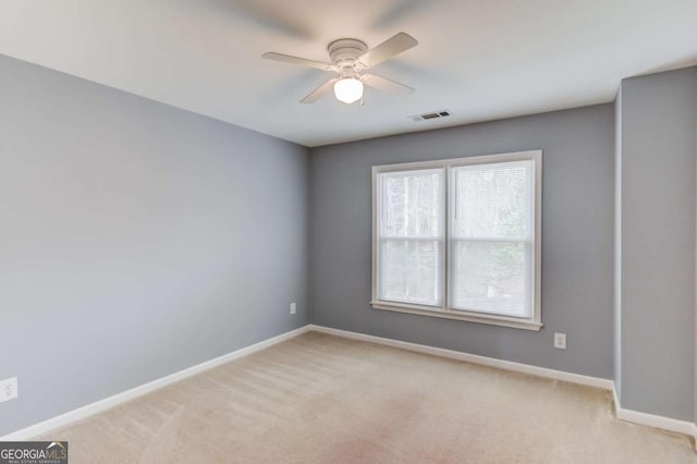 empty room featuring visible vents, light carpet, baseboards, and ceiling fan