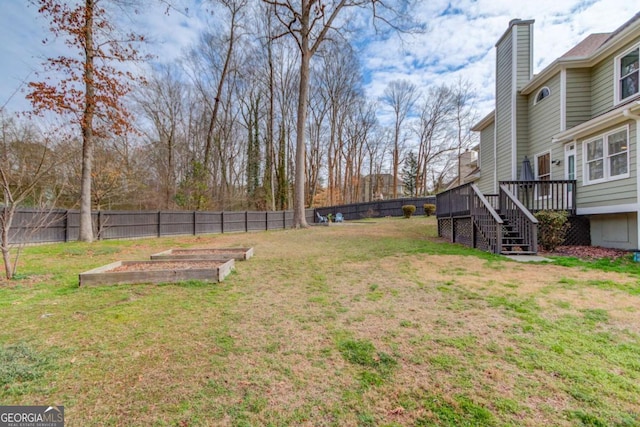 view of yard featuring a deck, a garden, stairs, and a fenced backyard