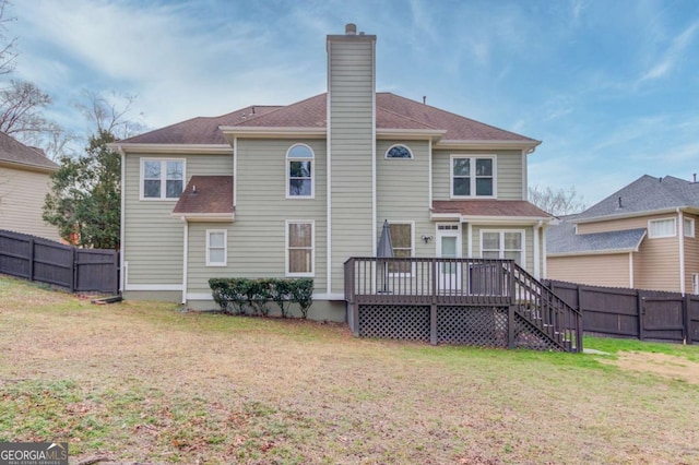 back of house with a wooden deck, a yard, a fenced backyard, and a chimney