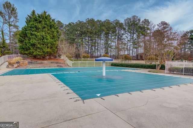 community pool with a patio and fence