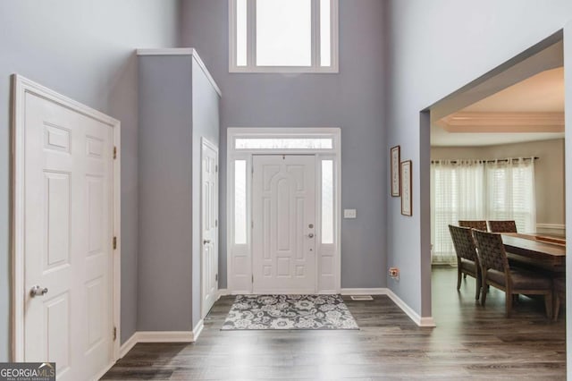 foyer with baseboards, dark wood-style flooring, and a towering ceiling