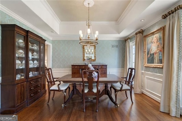 dining space featuring a tray ceiling, crown molding, a notable chandelier, and dark hardwood / wood-style flooring