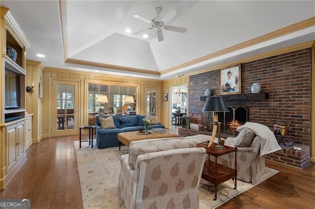 living room featuring a fireplace, ornamental molding, vaulted ceiling, ceiling fan, and wood-type flooring