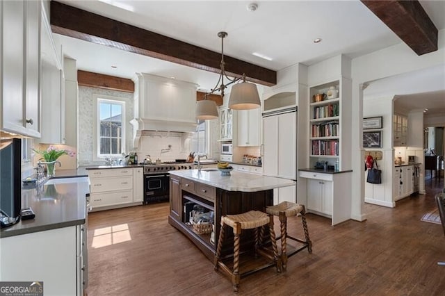 kitchen with custom range hood, white cabinets, pendant lighting, a kitchen island, and dark hardwood / wood-style floors