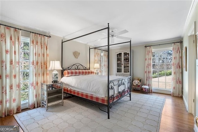 bedroom featuring hardwood / wood-style flooring, crown molding, and multiple windows