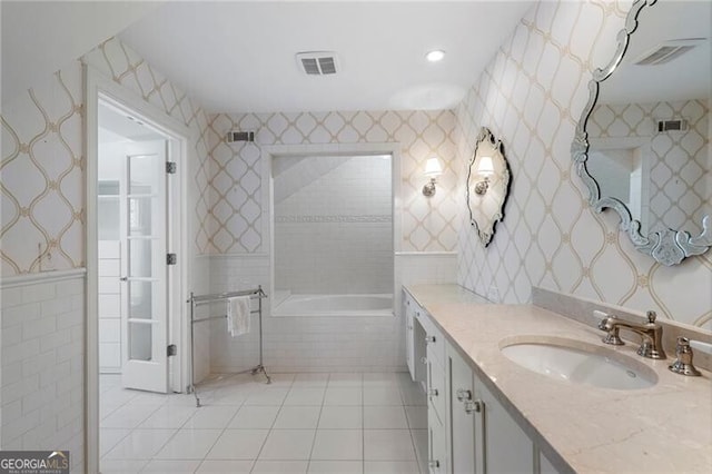 bathroom featuring tile walls, tile patterned flooring, vanity, and tiled tub