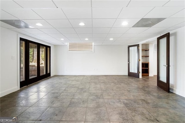 unfurnished room with a drop ceiling and french doors